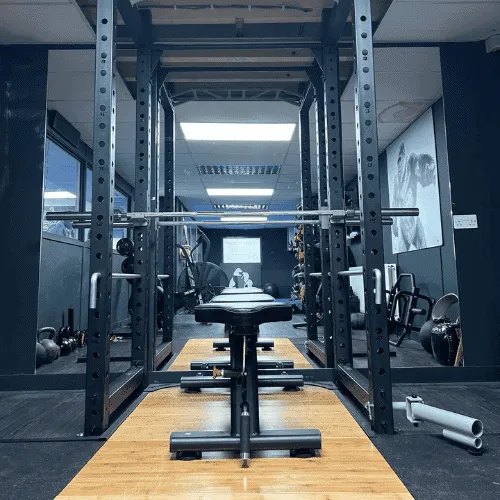 A power rack with a loaded barbell, ready for strength and conditioning class at ApeStrength.